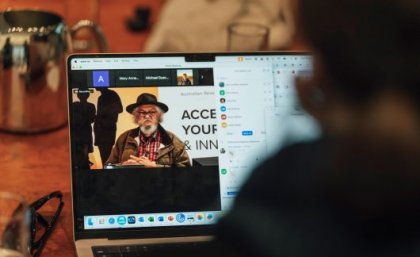 An image showing a laptop screen over a person's shoulder, with an Indigenous Australian on the screen.